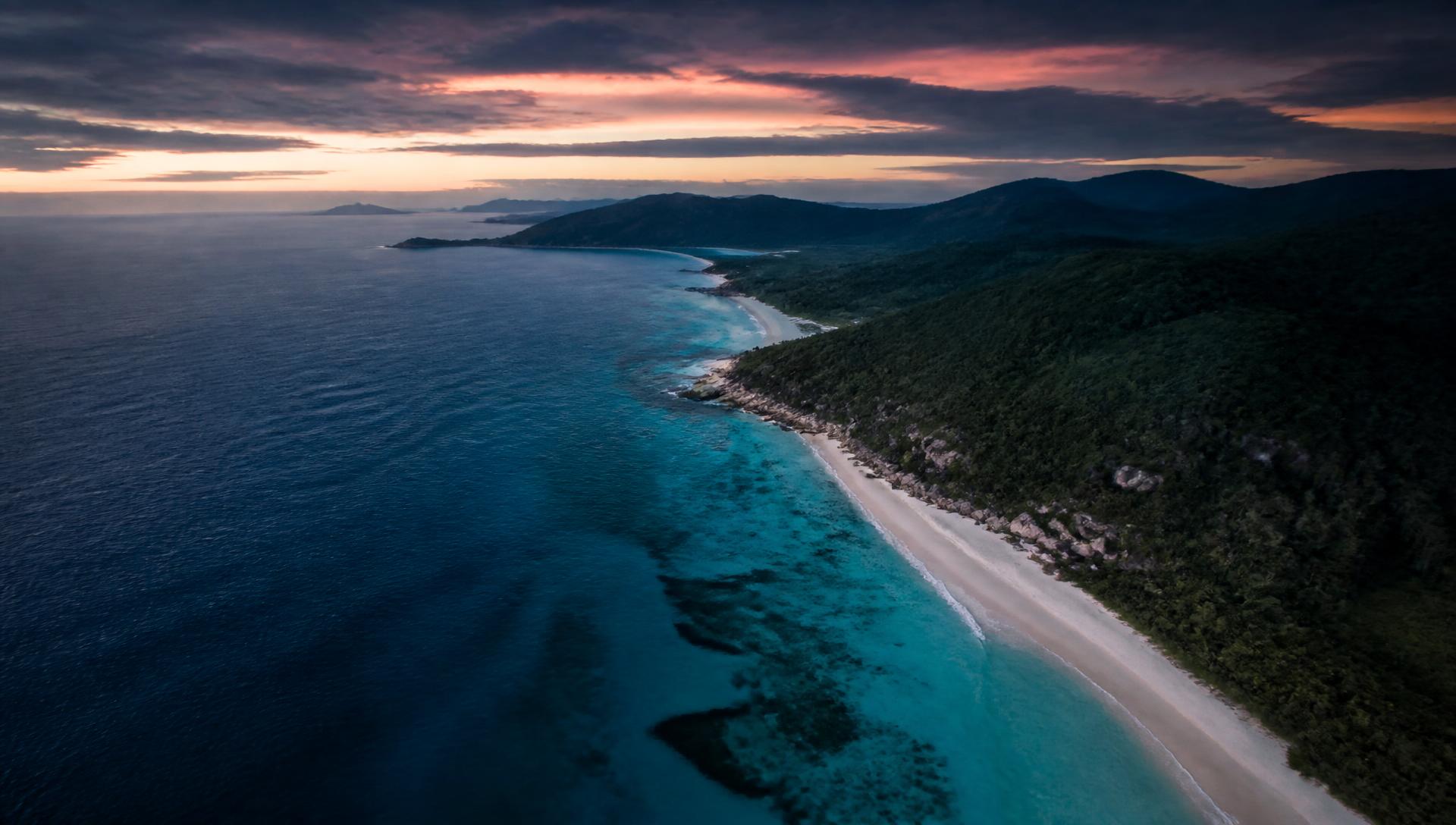 Aerial view of a turquoise tropical coastline at dusk